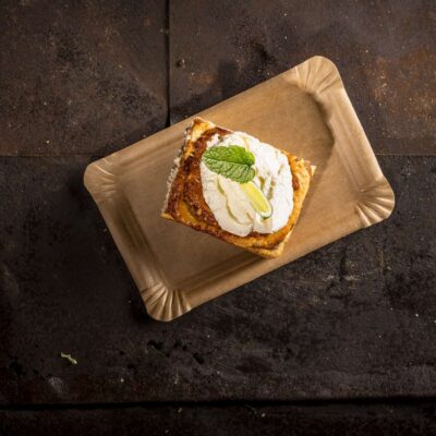 Ein kunstvoll angerichtetes Dessert auf einem Holztablett.