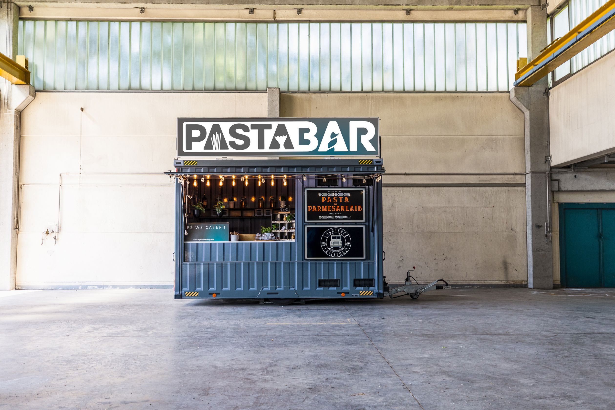 Ein foodtruck mit der aufschrift "pasta bar" steht in einer industriehalle.