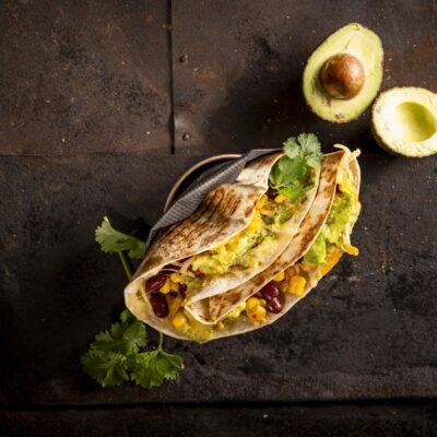 Leckeres Taco-Gericht angerichtet mit frischem Gemuese und Avocado.
