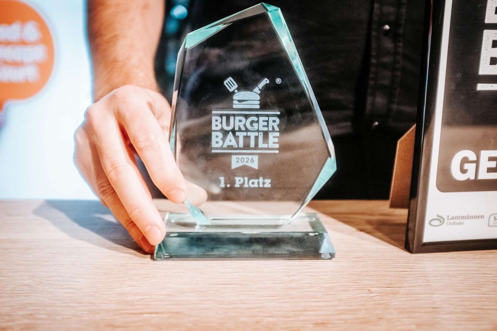 Hand haelt eine glaeserne Trophaee mit Gravur