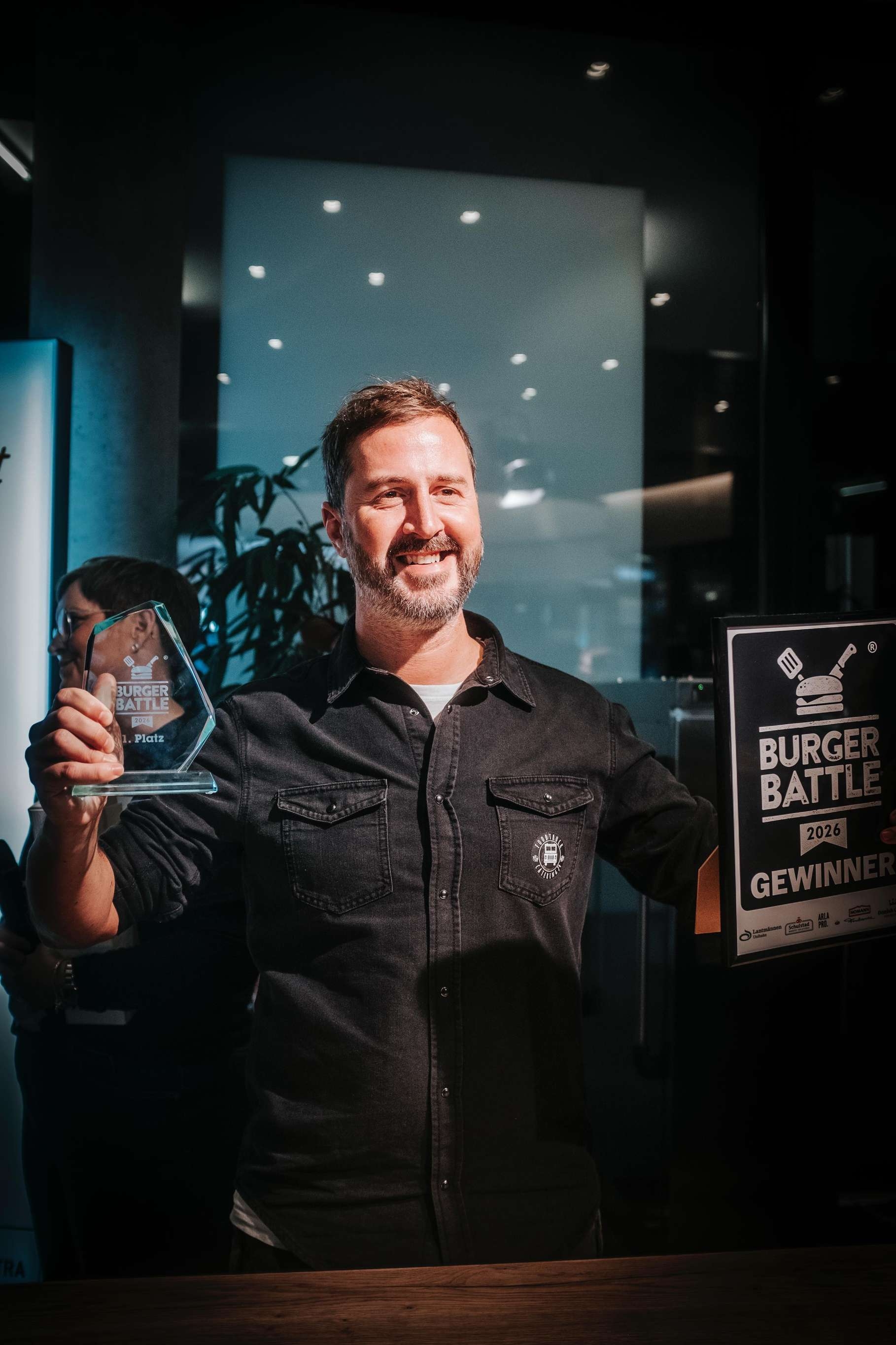 Ein Brauer zeigt stolz eine Urkunde und einen Bierkrug.