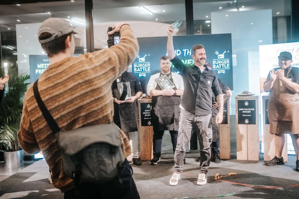 Eine Gruppe von Menschen nimmt an einer Feier teil, waehrend eine Person mit erhobenem Arm posiert.