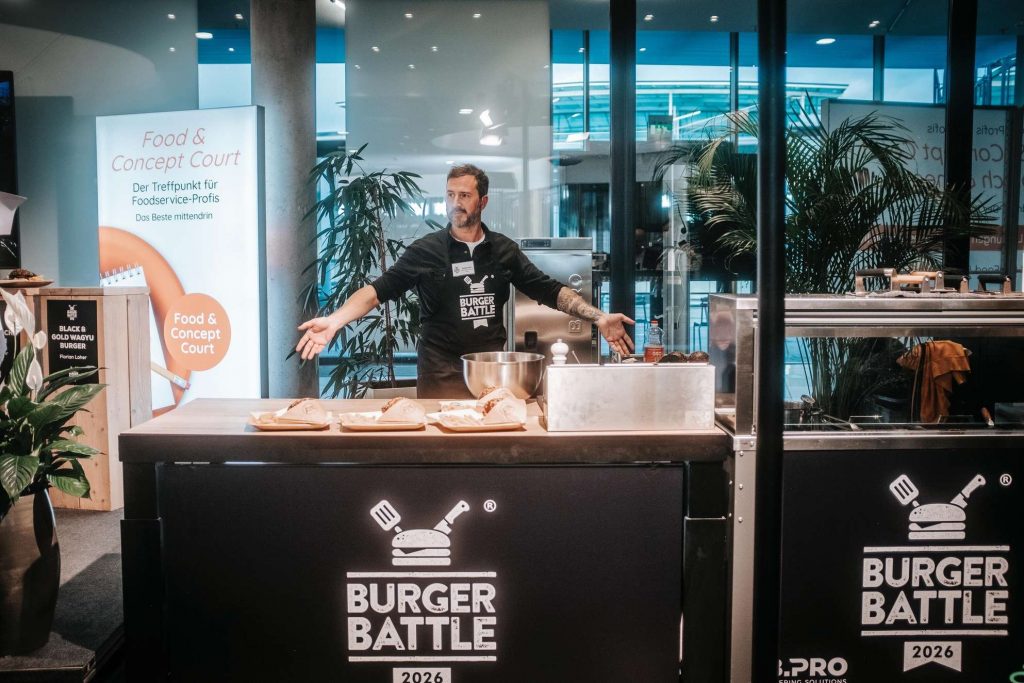 Mann hinter einem Burgerstand bei einem Food-Festival.